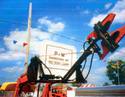 orange hydraulic tree clippers held high by tractor mount against blue sky