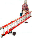 Man walking away dragging extension ladder on two-wheeled ladder dolly