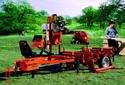Orange Wood-Mizer portable sawmill with seat and man stacking boards next to it