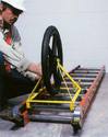 Man attaching a yellow Ladder Caddy with a single large wheel to a ladder lying on the ground