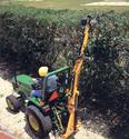 A swingtrim tree trimmer being used to trim the topside of a fencerow