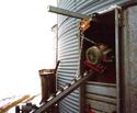 Auger engine being lifted out of a grain bin entrance by a winch