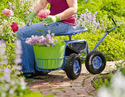 Gardener using the Roling Garden Work Seat to make cutting low flowers easy