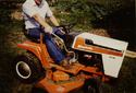 Man riding orange lawn tractor equiped with hand operated clutch/brake