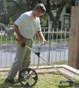 Man using a string trimmer equipped with large wheel for support and maneuverability