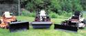 Three zero turn mowers equipped with Z-Mount power bars and a loader, broom, and snow plow