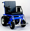 The chair with its two large drive wheels toward the back (battery and motor between them), two swivel wheels up front, and joystick on one of the armrests.