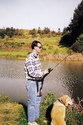 An adult male fishing in standing position with the handle-end of the rod securely inserted in the holder pipe.