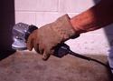 A hand-held power tool in the grasp of a workmanâ€™s anti-vibration-gloved hand.