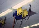 Mounted on the shop ceiling is a three-cord dispenserâ€”two smaller, open reels housing standard-size cords, and one larger, enclosed reel housing a heavy-duty cord.