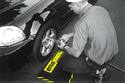 An adult male, with both legs kneeling on the mat, is changing an auto front left tire.