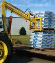 Mounted behind a tractor is the twin-arm, double-cylinder boom lift that is hoisting a pallet containing 30 large bags of material.