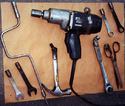 Lying on a plywood sheet are nine shop tools onto which farmer has welded bolt stubs that he can screw into his prosthetic device.