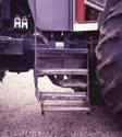 The photo shows the tractorâ€™s original three-step ladder with the added bottom retractable step and added left-side hand rail.