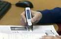Photo of a person's right arm in a blue sweater scanning  a magazine with a pen scanner