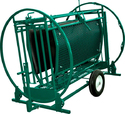 Green metal cage-like device with 2 large round metal tubes on ends to rotate entire work chute once animal is inside. Includes vertical head-lock bars & unit is on 2 black tires for portability.