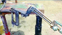 C-clamp fastened to welding table with a 6-inch flat iron piece welded on top of C-clamp. 2 pieces of half-inch pipe welded on end of flat bar-1 vertically-other horizontally to hold welding torch nozzle