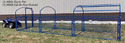 Blue metal tubular rectangular framing with metal mesh panels on the side and curved tubular framing over the top for a tarp cover - all hitched to an ATV for skidding in a pasture. 2-tone gray & brown pole barn in background