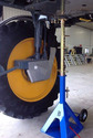 A blue white and gold jack under an agricultural sprayer with high ground clearance inside a shed