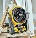 Yellow & black portable worksite fan with battery pack installed sitting on a work table