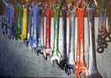A row of painted combination wrenches hanging on nails attached to a board that is fastened to a wall.