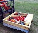 Pallet-sized box with wood dividers to carry different tools built onto a wooden pallet that's being carried by a skid loader pallet forks.