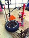 Pallet on a pallet jack in a shop with a tire and tire tools on the pallet.