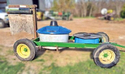 Small hand-pulled wagon with water pot in front - mineral pot in back - and protein lick with fly-control curtain fastened to rear.