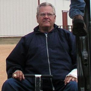 Hubert Von Holten sitting in scooter looking up at man using a lift to get into a truck