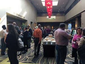 Hotel hallway in Lincoln, Nebraska with conference participants mingling during break. Table with food in middle of photo.