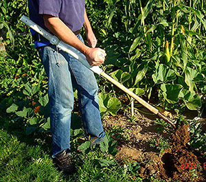 Man using hoe modified with handle and belt attachment