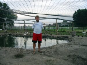 Marvin standing next to pond with netting above to keep wildlife in