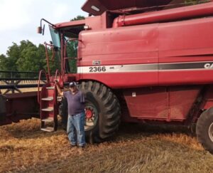 Alan stands next to combine in field