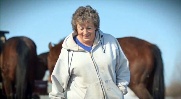 Jackie walking outside with horses in background