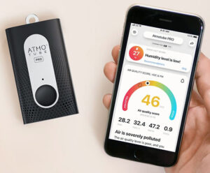Rectangular air quality monitor next to hand holding cell phone