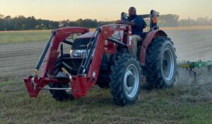 Davon Goodwin plowing with red tractor in field