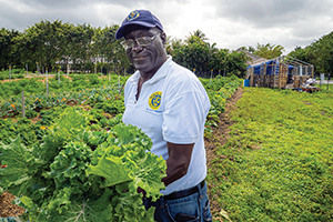 Man holding large bunch of greens while smiling at camera