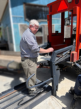 Bill Field stand one platform of lift attached to back of tractor