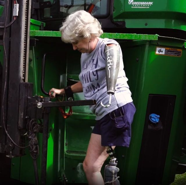 Laurie Hayn, using prosthetic arm and prosthetic leg, stands on lift that raises her to cab of tractor.